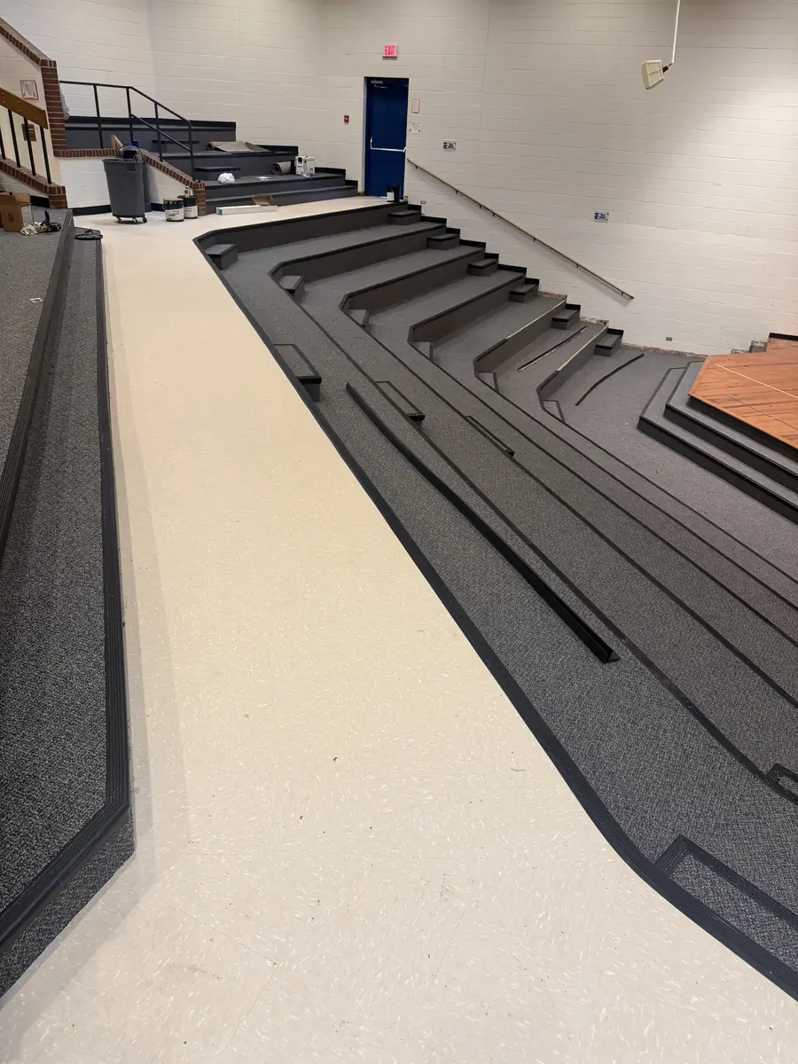Auditorium flooring with carpeted tiered steps and a resilient vinyl aisle