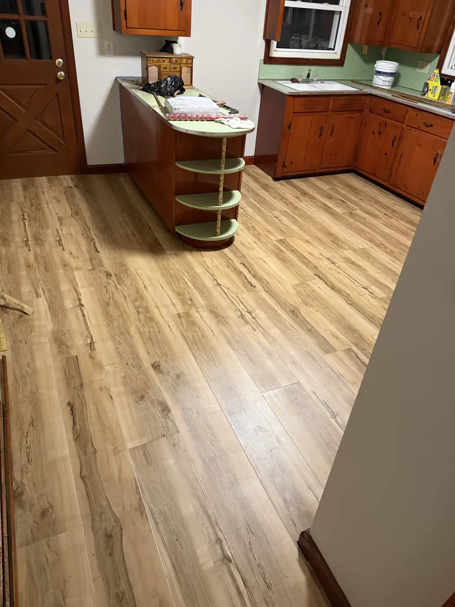 Wood-look luxury vinyl plank flooring installed in a kitchen with wood cabinets near Hickory NC